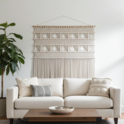 Living room with a beige sofa, decorative pillows, and a large macrame wall hanging.